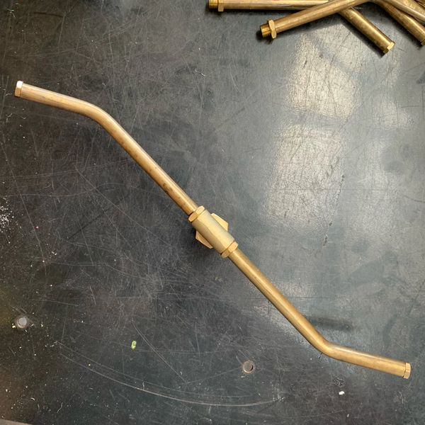 Copper pipe with angled bends and connector on a dark surface.