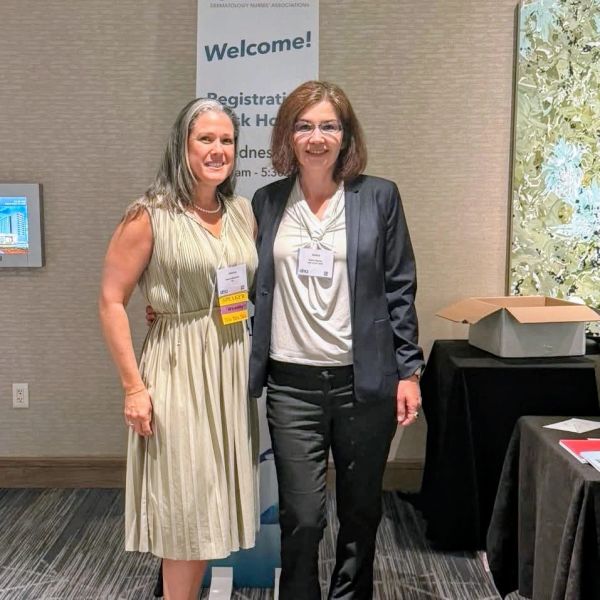 Two women smiling at a conference event.