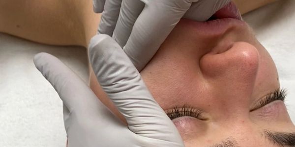 A person receiving a facial treatment with gloved hands gently touching the face.