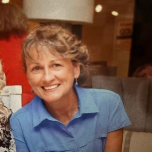 Two women smiling together at a table, one wearing sunglasses.