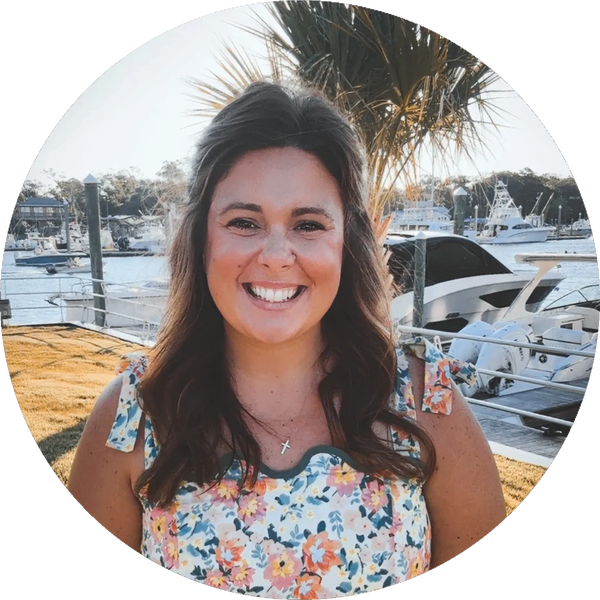Smiling woman in floral dress by the marina on a sunny day.