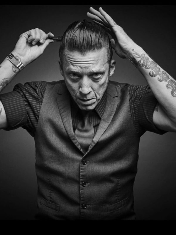 Man styling slicked-back hair in black and white photo.