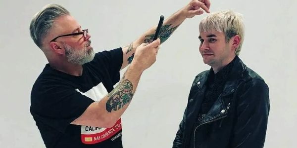 A stylist trims a man's hair while holding a comb.