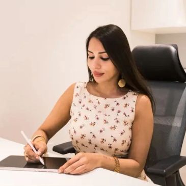 Woman using a digital pen on a tablet at desk.