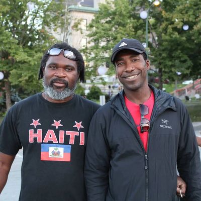 Deux hommes souriants posant ensemble en extérieur.