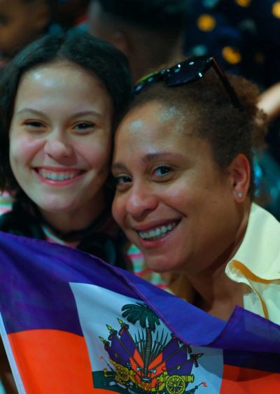 Deux femmes souriantes tenant un drapeau haïtien.