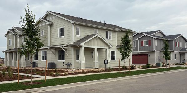 Modern townhouses with small trees and cloudy sky.