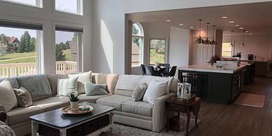 Cozy open living room with large windows and kitchen area.