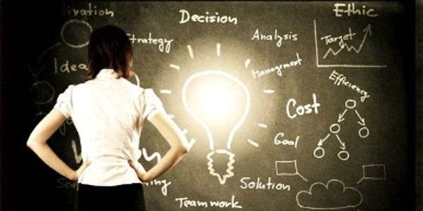 Woman standing in front of a chalkboard with business-related words.