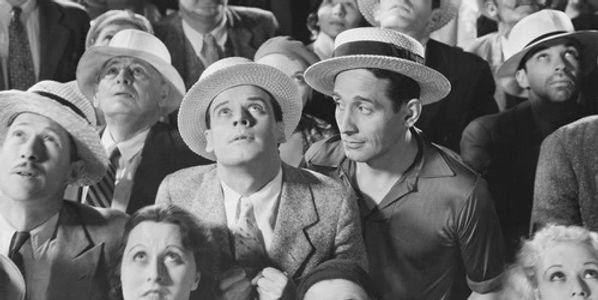A crowd of people wearing hats looking intently upward.