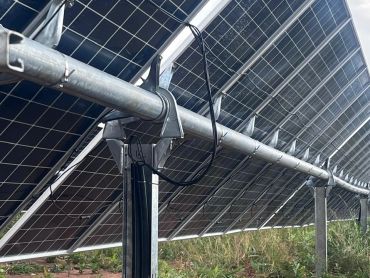 Close-up of solar panels with wiring and metal supports in a field.
