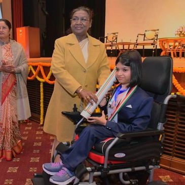 Young girl in wheelchair receiving an award with officials.