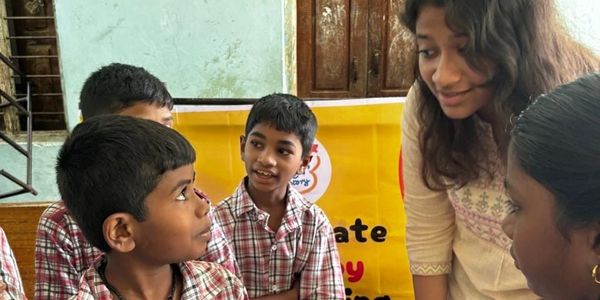 A woman engaging with three boys in checkered shirts indoors.