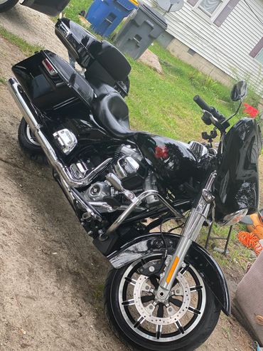 Shiny black touring motorcycle parked outdoors near a house.