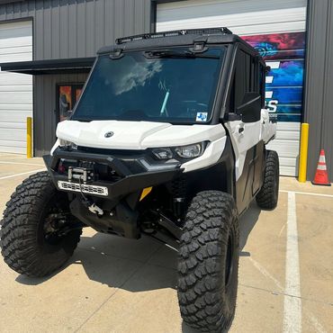 Off-road utility vehicle with large tires and rugged design parked outside.