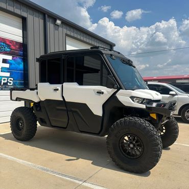 A rugged off-road vehicle with large tires parked outside a building.