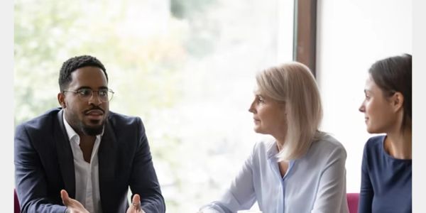 Three professionals having a discussion in a bright office.
