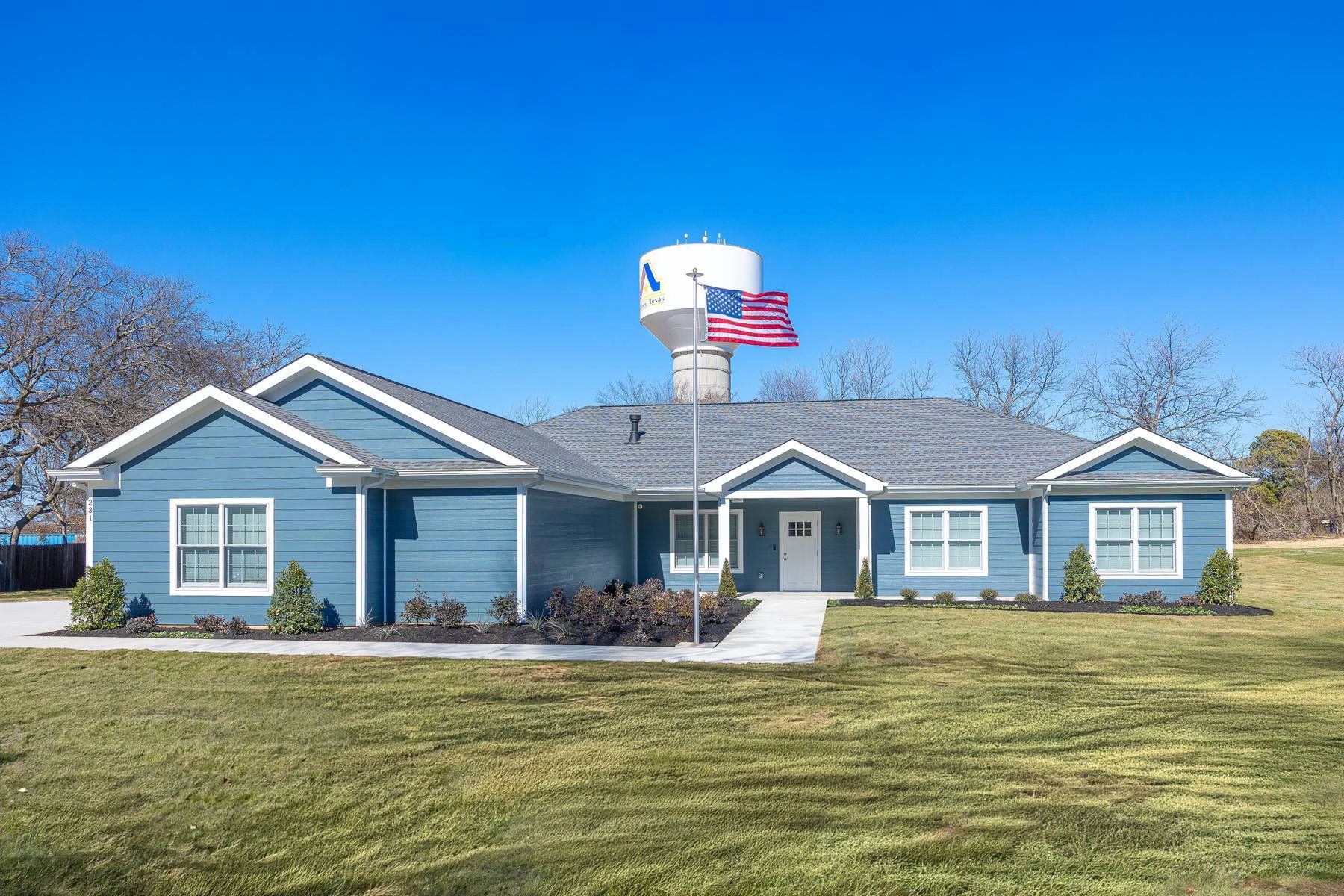 Blue house with American flag and water tower in background.