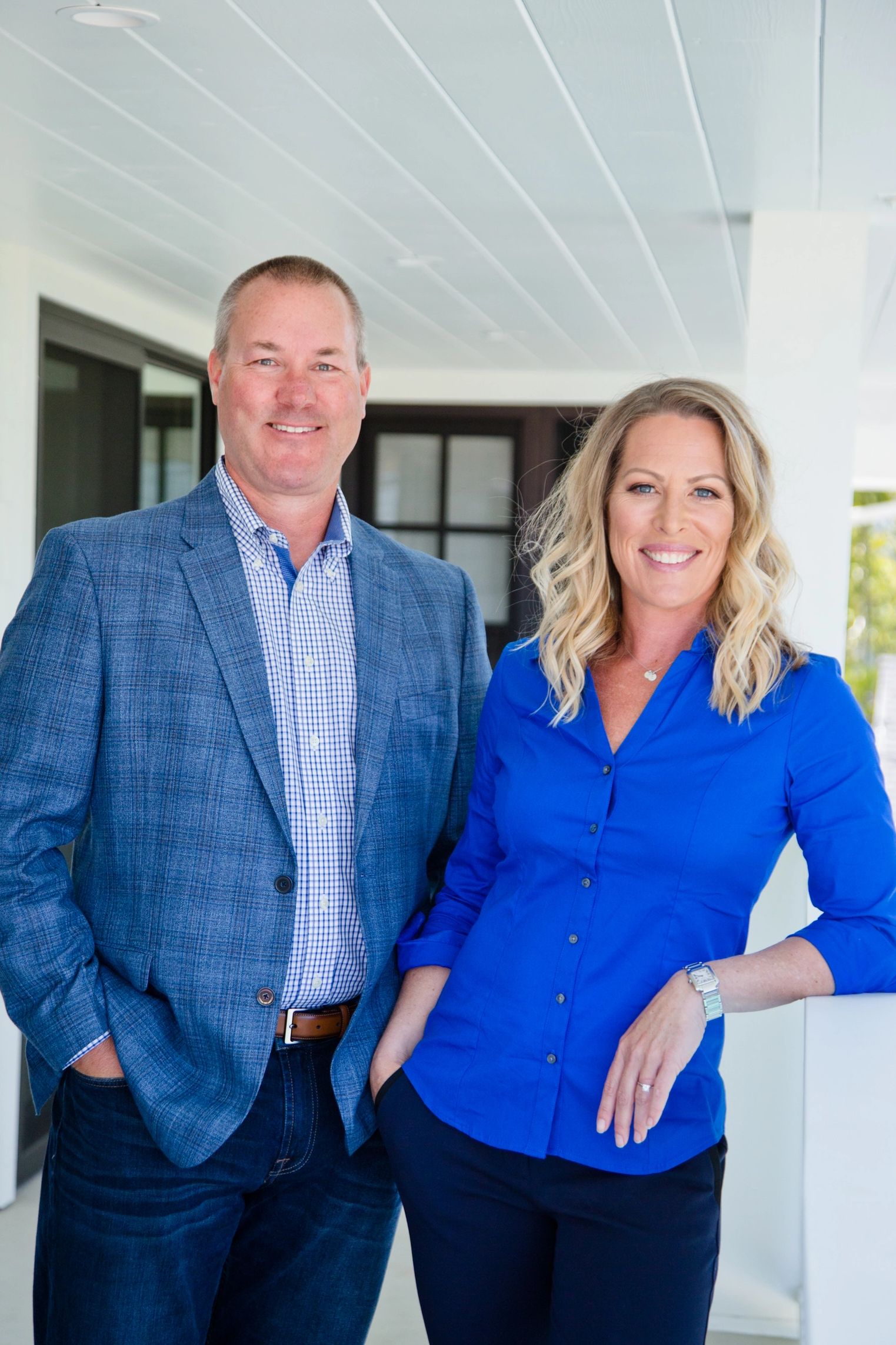 Two smiling professionals in business casual attire standing side by side.