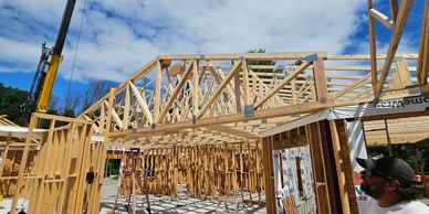 Wooden framework of a house under construction on a sunny day.