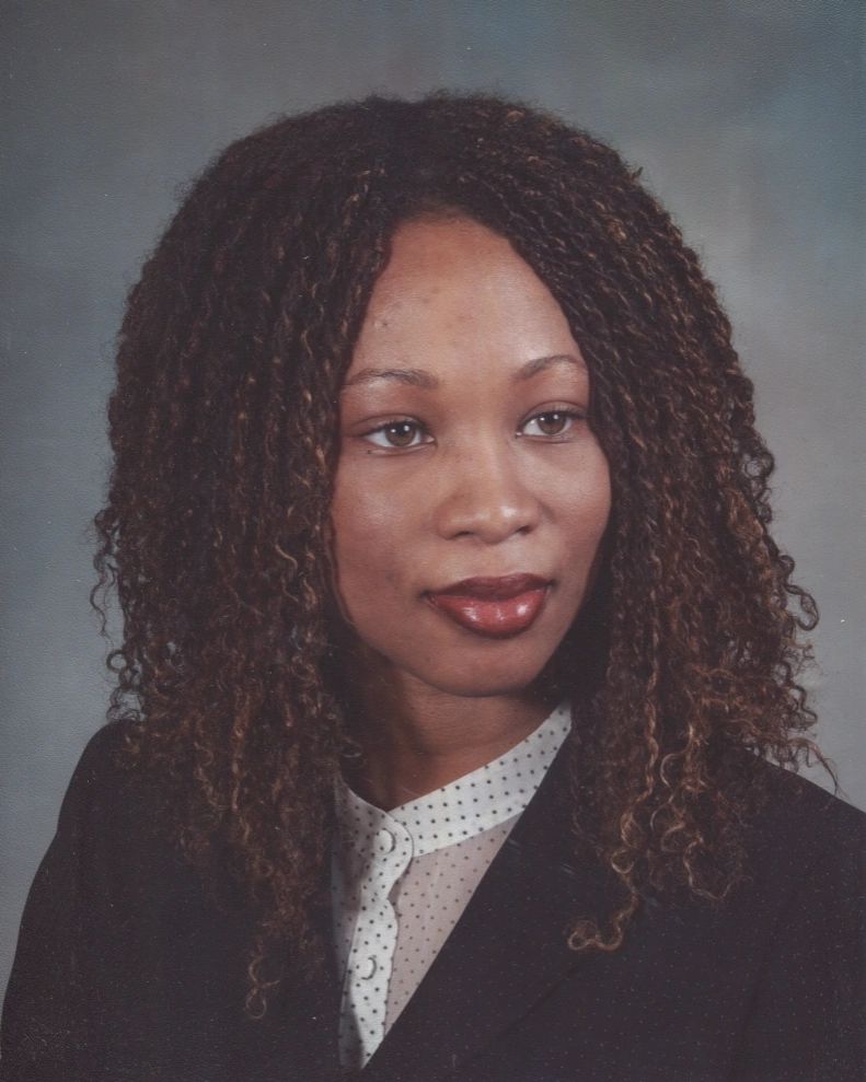 Professional portrait of a woman with curly hair in a dark blazer and white polka dot blouse.