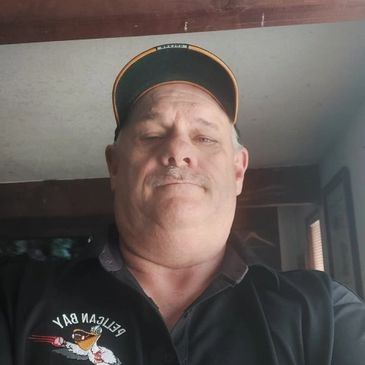 Man wearing a cap and black shirt indoors.