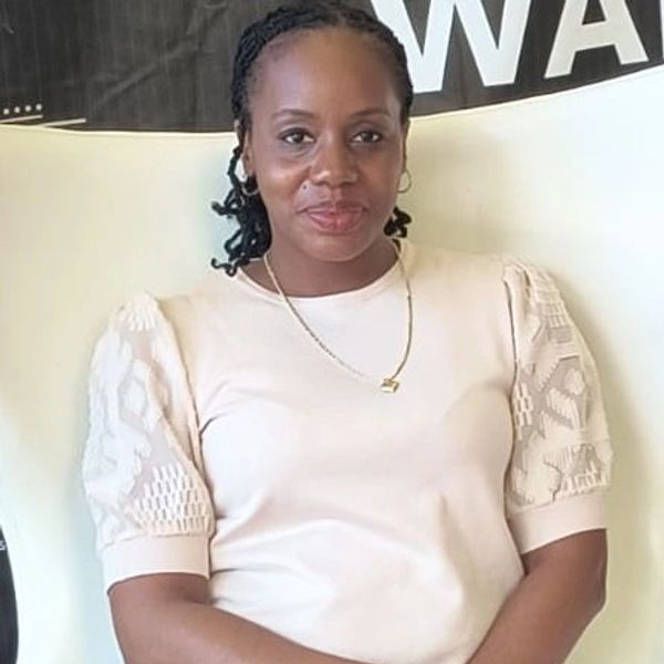 Claudia Johnson with braided hair wearing a white shirt and gold necklace.