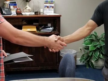 Two people shaking hands in an office setting.