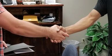 Two people shaking hands in an office setting.