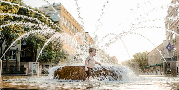 Fine Art Children's Portrait editorial vibe Charleston SC boy runs through fountain waterfront park 