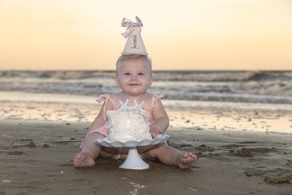 Fine Art Cake Smash Charleston SC 1 year old girl on beach with cake pinks and yellows in sky
