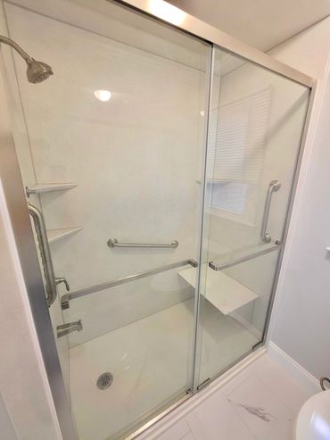 Jacuzzi walk-in shower with white walls and a sliding glass door