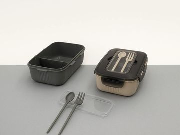 Two lunch containers with utensils on a gray surface.