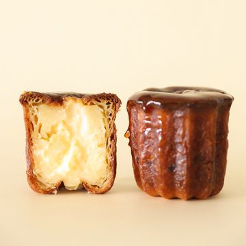 Two cannelés, one cut open showing creamy interior.