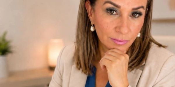 Mujer pensativa con maquillaje y joyería.
