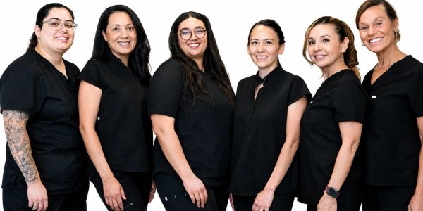 Six women in black uniforms smiling at the camera.