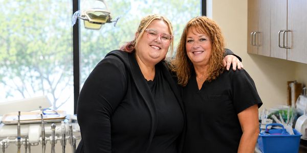 Two women smiling in a dental office setting.