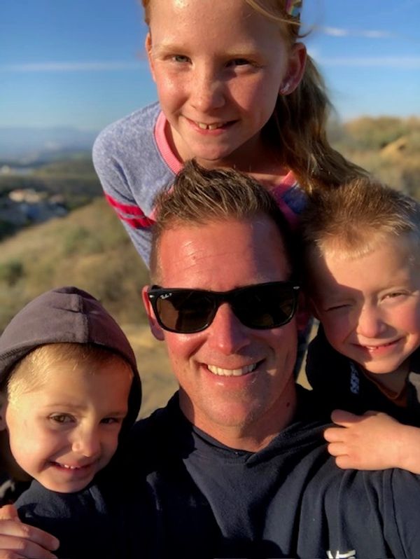 Smiling man with three happy children outdoors.