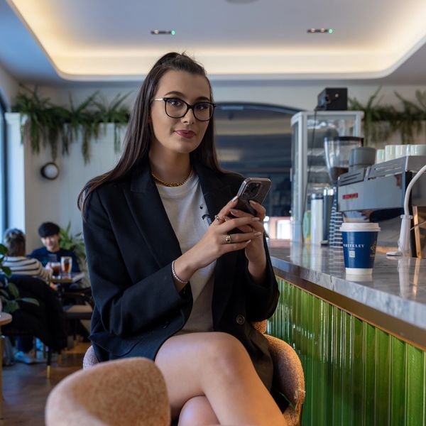 Isabella Hutton sitting in a cafe with her phone in hands