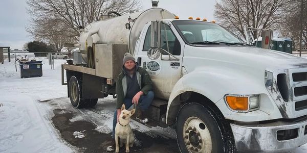 co-owner with dog posed in front of a vacuum truck