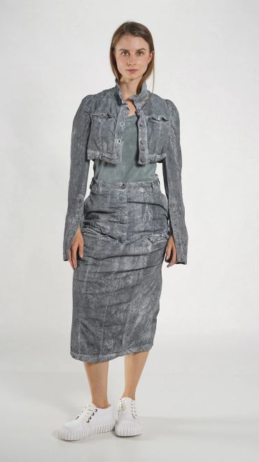Model wearing a gray textured skirt and cropped jacket with white sneakers.