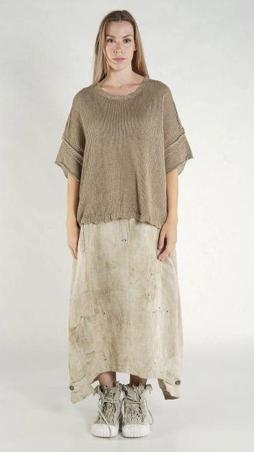 Woman wearing a loose brown knitted top and a long beige skirt with high-top sneakers.