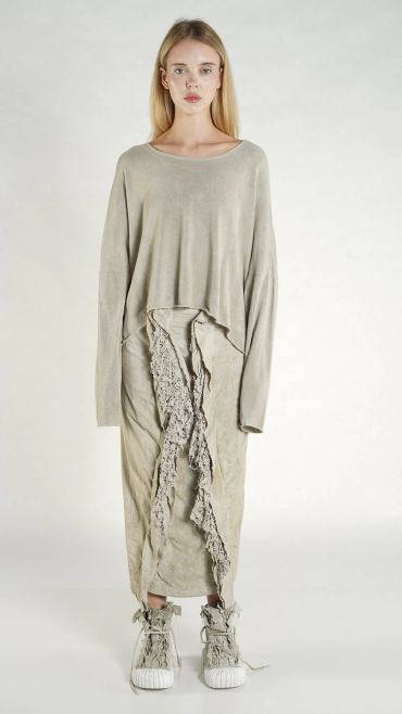 Model wearing a beige oversized top and skirt with lace details and matching sneakers.
