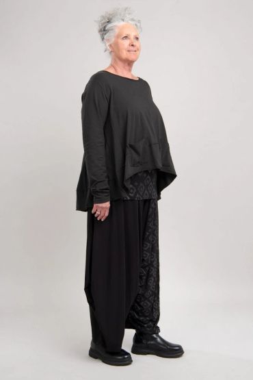Femme âgée en tenue noire élégante sur fond gris.