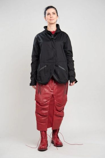 Femme en veste noire, pantalon rouge et bottes rouges.