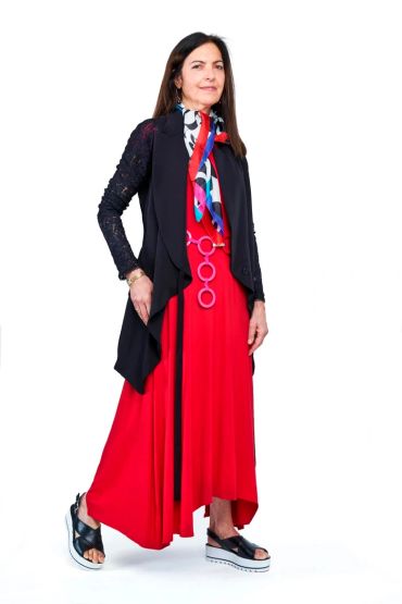 Woman in a red dress with a black vest and colorful scarf.