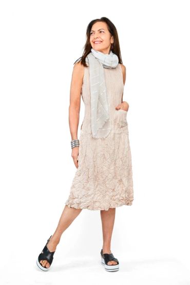 Woman in a beige textured dress with a light scarf and black platform sandals.