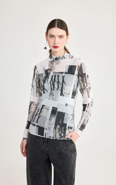 Woman wearing a patterned sheer long-sleeve top with black jeans.