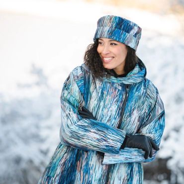 Woman smiling in a blue patterned winter outfit in snow.