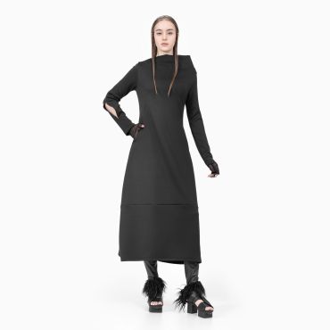 Woman in a long black dress with cut-out sleeves and feathered heels.